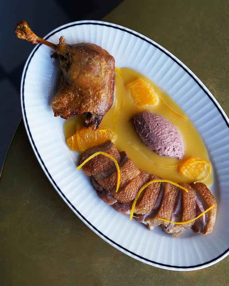 Duck a l'orange served on an oval plate at Poodle Bar & Bistro