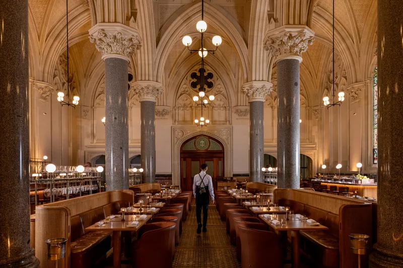 Vaulted gothic dining room with leather booths and globe chandeliers at Reine & La Rue